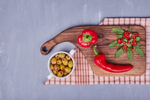 Red hot chilipepers met gemarineerde olijven op een houten bord.