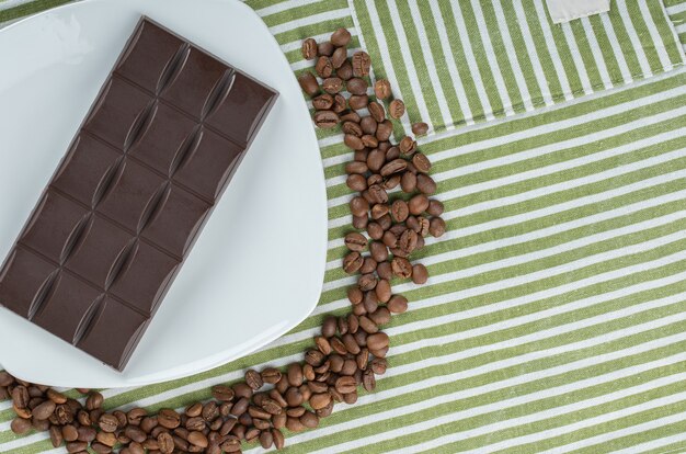 Reep chocola met koffiebonen op een tafellaken.