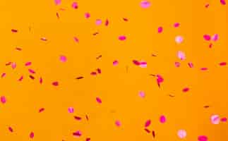 Gratis foto regeling van partij rode confetti op oranje muur