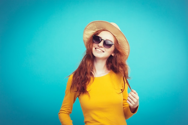 Reis concept - Close-up Portret jonge mooie aantrekkelijke roodharige meisje wtih trendy hoed en zonnebril lachend. Blauwe Pastelachtergrond. Kopieer de ruimte.