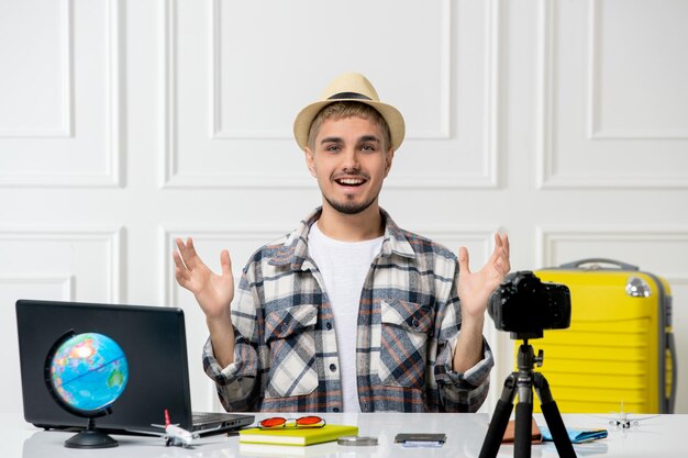 Reisblogger knappe jonge kerel die reisvlog op camera opneemt met gele bagage zwaaiende handen