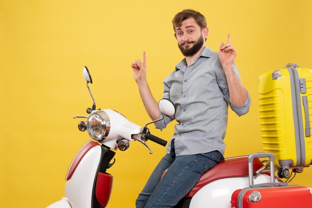 Reisconcept met jonge zelfverzekerde bebaarde man zittend op motocycle op het omhoog op geel