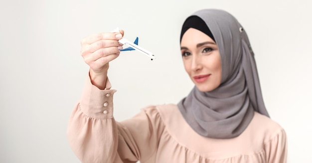 Reizend concept. arabische moeder in hijab met vliegtuigmodel, selectieve focus, kopieer ruimte