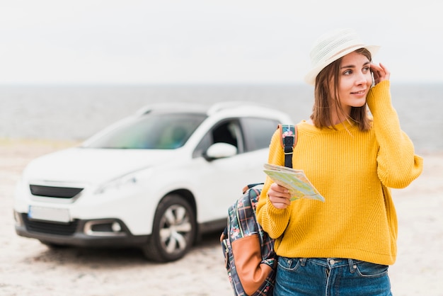 Gratis foto reizende vrouw met auto op de achtergrond