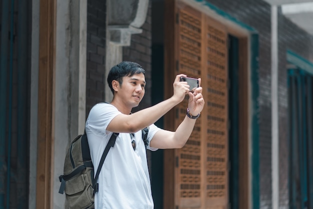 Reiziger de Aziatische mens die mobiele telefoon met behulp van voor neemt een beeld terwijl het besteden vakantiereis in Peking, China