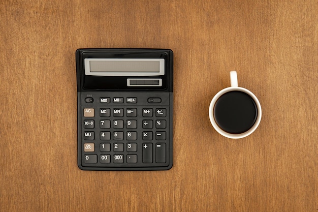 Rekenmachine en een kopje koffie op een houten achtergrond