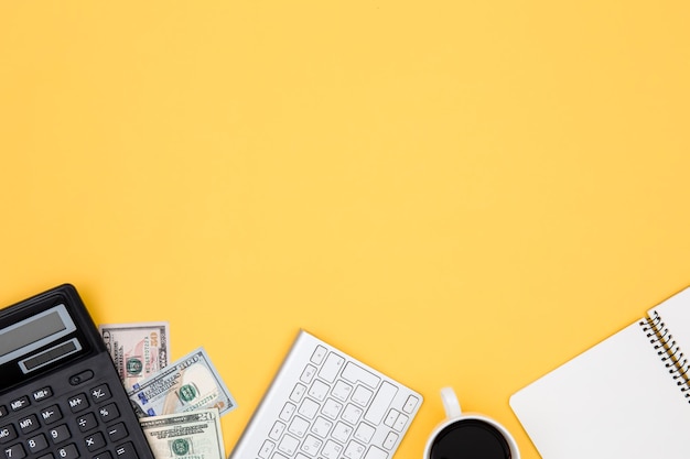 Rekenmachine geld notitieblok en toetsenbord op gele achtergrond plat lag