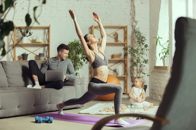 Rekken voor de bank. Jonge vrouw die fitness, aerobics, yoga thuis, sportieve levensstijl en thuisgymnastiek uitoefent.