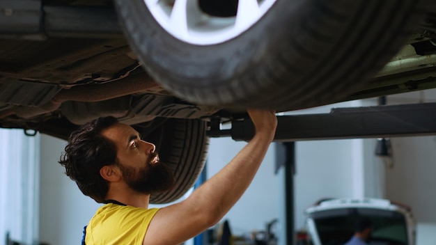 Gratis foto reparateur inspecteert auto op bovenlift