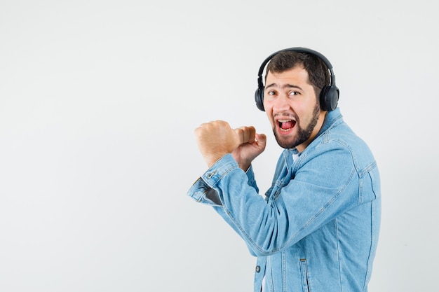 Retro-stijl man luisteren muziek met koptelefoon in jasje, t-shirt en op zoek geamuseerd, vooraanzicht. ruimte voor tekst