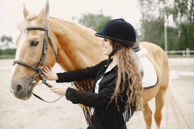 Rider vrouw praten met haar paard op een ranch. vrouw heeft lang haar en zwarte kleding. vrouwelijke ruiter wat betreft haar bruin paard.
