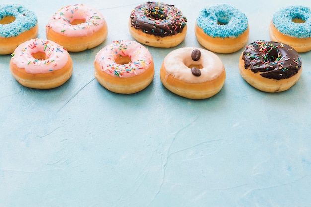 Gratis foto rij van decoratieve donuts op blauwe achtergrond
