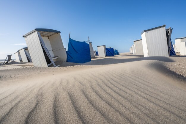 Rij van individuele witte kleedkamerkluizen en kleedhokjes op een zandstrand