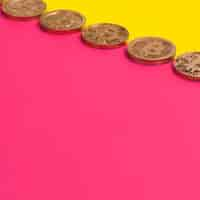 Gratis foto rij van vele bitcoins over de gele en roze dubbele achtergrond