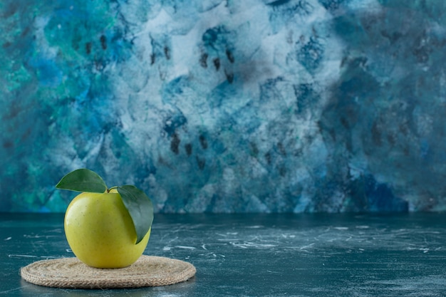 Rijpe appel op een onderzetter, op de marmeren tafel.