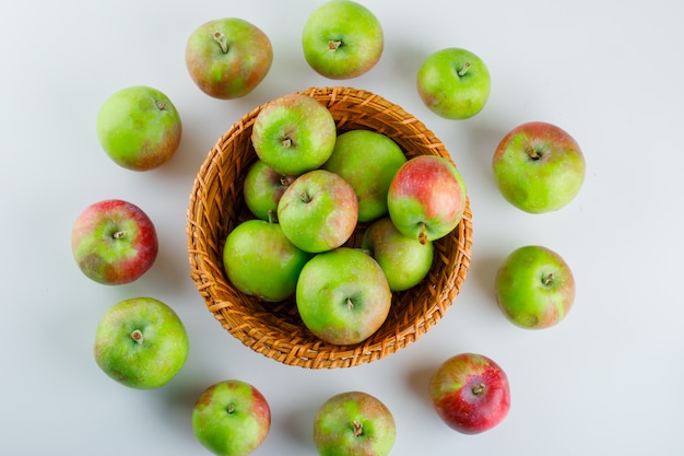 Rijpe appels in een rieten mand op wit. plat leggen.