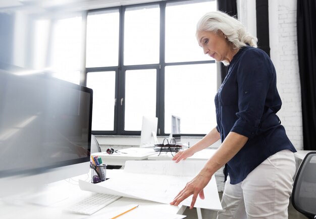 Rijpe bedrijfsvrouw die een grafiek analyseren die voor haar wordt gehouden