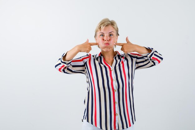 Rijpe blonde vrouw in een overhemd met verticale strepen