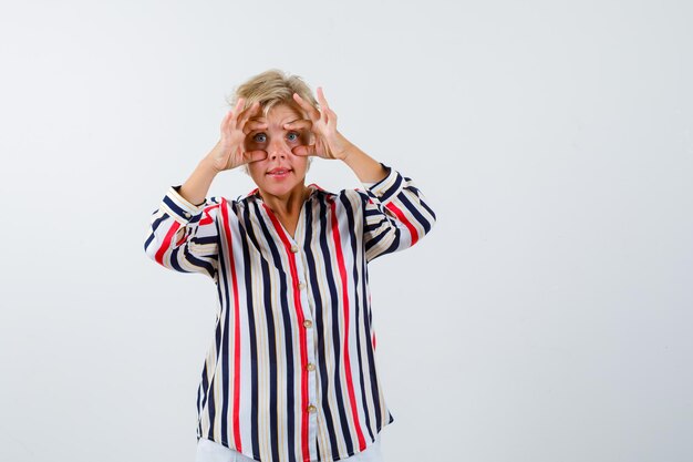 Rijpe blonde vrouw in een overhemd met verticale strepen