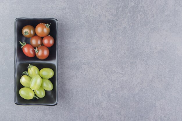 Rijpe en onrijpe tomaten op het bord, op het marmeren oppervlak