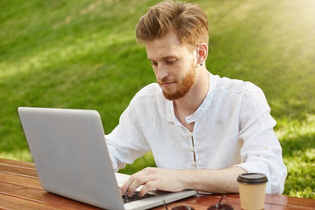 Rijpe gember knappe man met laptopcomputer in het park