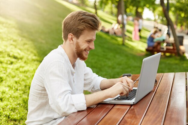 Rijpe gember knappe man met laptopcomputer in het park