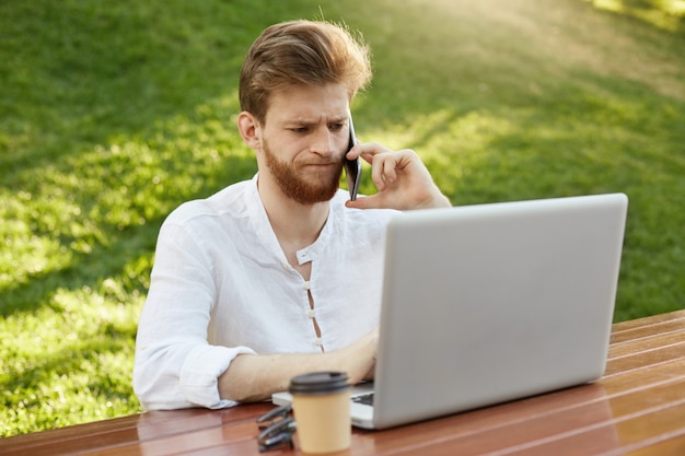 Rijpe gember knappe man met laptopcomputer in het park