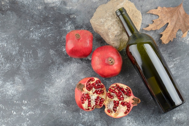 Rijpe granaatappelvruchten met een fles wijn op marmeren achtergrond. Premium Foto