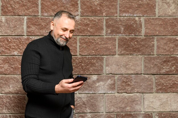 Rijpe mens die op zijn telefoon met exemplaarruimte kijkt