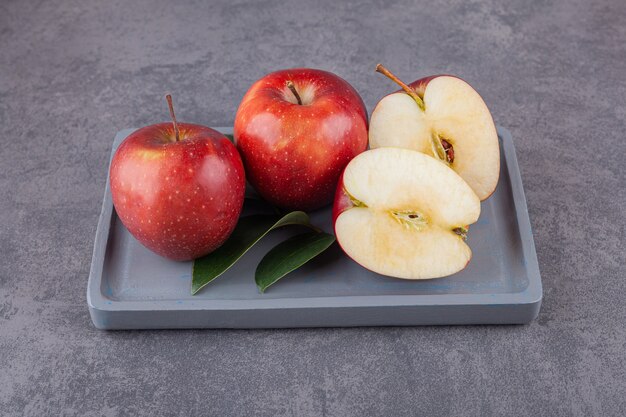 Rijpe rode appels met bladeren op een stenen oppervlak.