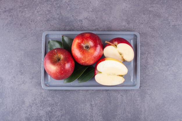 Rijpe rode appels met bladeren op een stenen oppervlak.