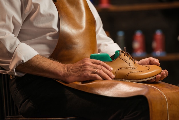 Rijpe schoenmaker die in workshop schoenen maakt