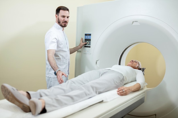 Gratis foto rijpe vrouw die een ct-scan ondergaat terwijl een medisch technicus toezicht houdt op de procedure in het ziekenhuis