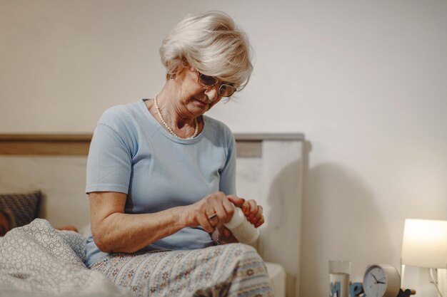 Rijpe vrouw die een pil neemt terwijl ze 's nachts op bed zit