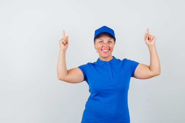 Rijpe vrouw die in blauw t-shirt benadrukt en gelukkig kijkt.