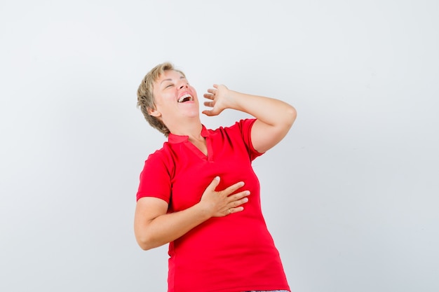 Rijpe vrouw die luid in rood t-shirt lacht