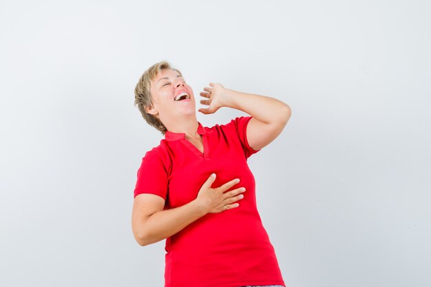 Rijpe vrouw die luid in rood t-shirt lacht