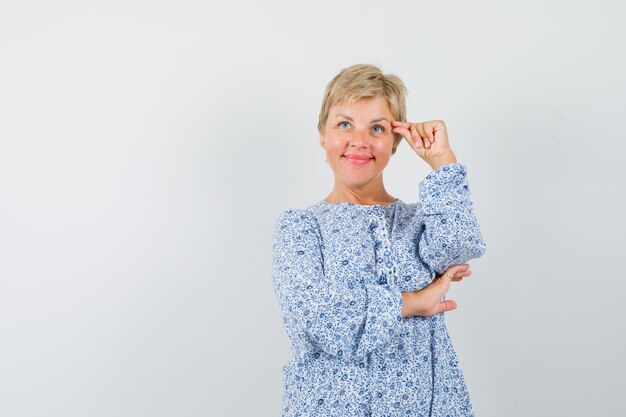 Rijpe vrouw die make-up in kleding beweert te doen en hoopvol kijkt.