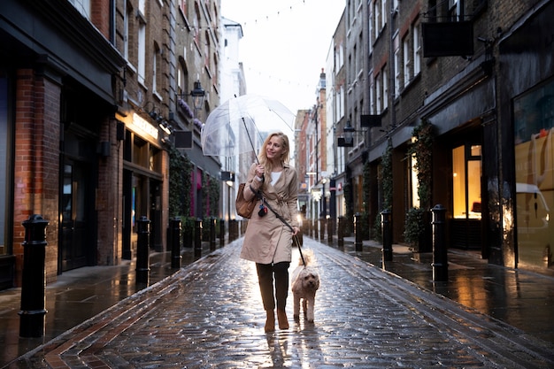 Rijpe vrouw die met haar hond loopt terwijl het regent