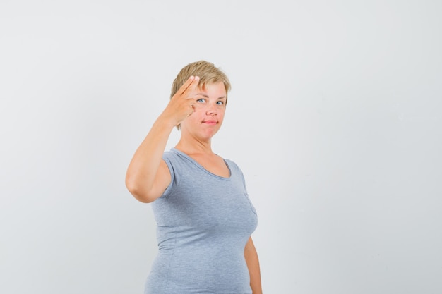 Gratis foto rijpe vrouw die met hand en vingers in grijs t-shirt gebaart en zelfverzekerd kijkt.