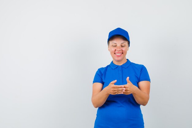 Rijpe vrouw die naar iets keek, deed alsof ze in een blauw t-shirt werd vastgehouden