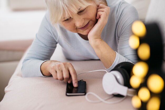 Rijpe vrouw die smartphone op bank gebruiken