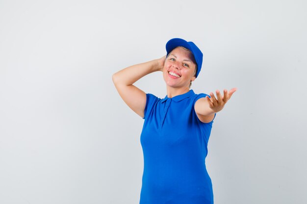 Rijpe vrouw die zich voordeed tijdens het uitrekken dient t-shirt in en kijkt vrolijk.