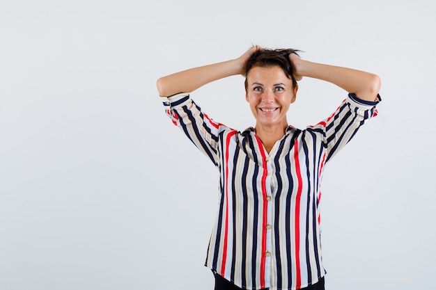 Rijpe vrouw hand in hand op het hoofd in gestreepte blouse en op zoek drijvend, vooraanzicht.