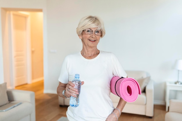 Gratis foto rijpe vrouw maakt zich klaar voor een training oudere vrouw klaar om te trainen verfrissing na de training sportieve oude vrouw die water drinkt