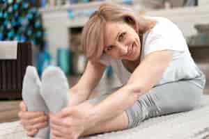 Gratis foto rijpe vrouw zittend op de vloer op yogamat