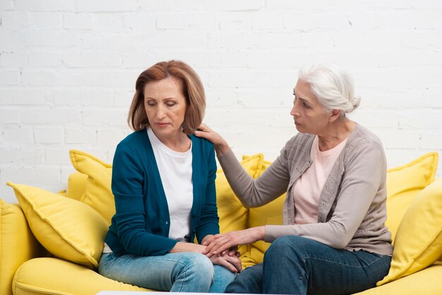 Rijpe vrouwen die op een laag zitten