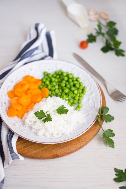 Rijst met groenten en peterselie op houten plank in de buurt van servet en vork