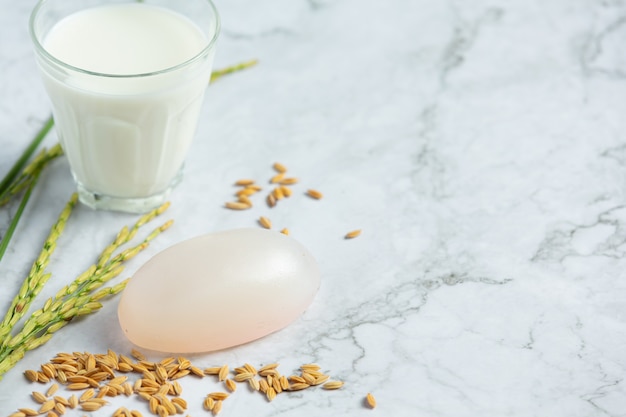 Rijstmelkzeep, glas melk, rijstplanten en rijstzaden op een witte marmeren vloer