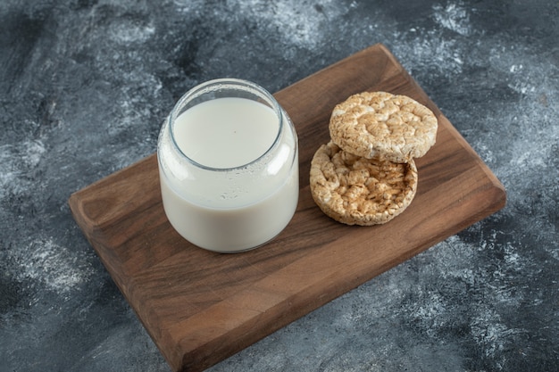 Rijstwafels en glas melk op een houten bord